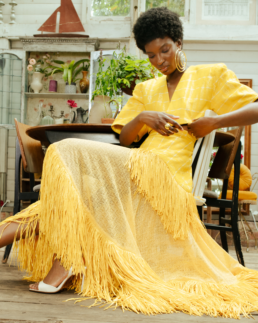 elegant stylish black woman in a yellow rafia suit and skirt set and spiral gold hoop earrings