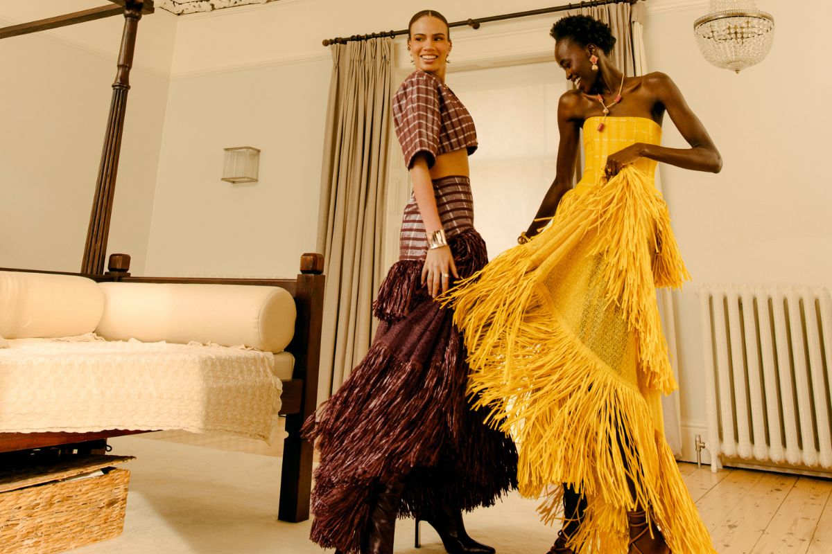  2 happy women dancing in handcrafted African fringe dresses, tassels and movement, artisan womenswear UK